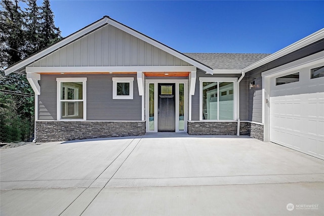 view of front facade featuring stone siding, a shingled roof, and a garage