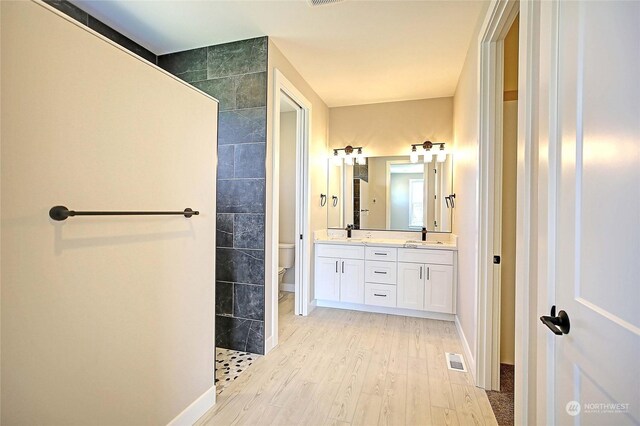 bathroom featuring a shower, wood-type flooring, toilet, and vanity