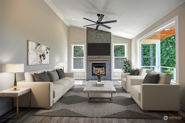 living room featuring hardwood / wood-style flooring, ceiling fan, vaulted ceiling, and a fireplace