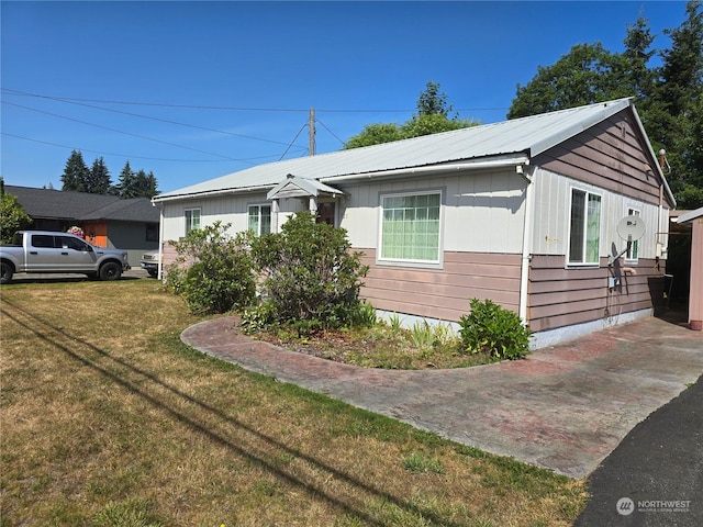 view of front facade featuring metal roof and a front lawn