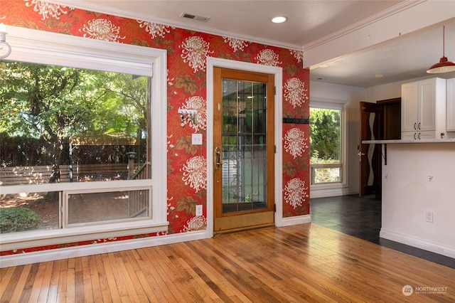 interior space featuring hardwood / wood-style flooring, baseboards, visible vents, and wallpapered walls