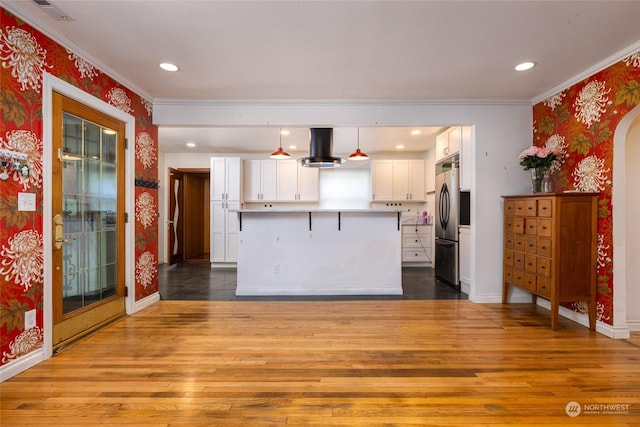 kitchen with wood finished floors, white cabinetry, freestanding refrigerator, island exhaust hood, and wallpapered walls