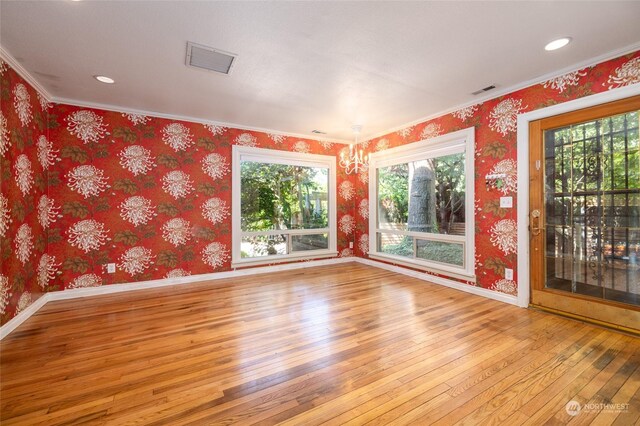 unfurnished room with a notable chandelier, light hardwood / wood-style flooring, and ornamental molding