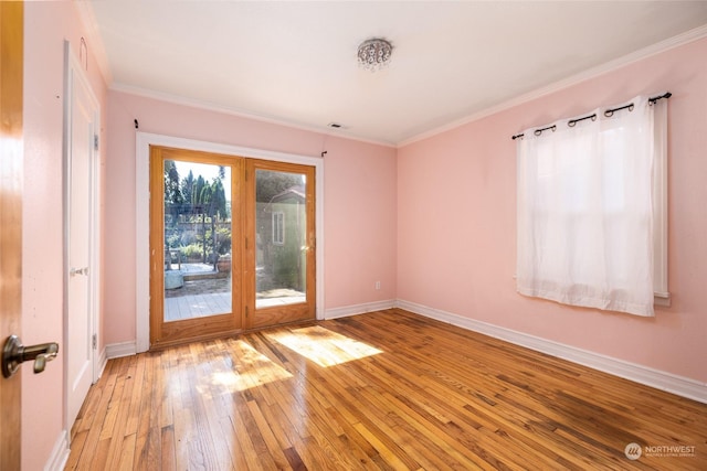 empty room with light wood-type flooring, crown molding, and baseboards