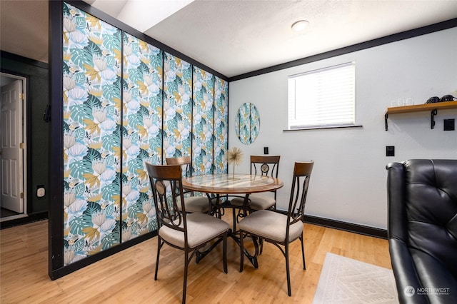 dining space featuring light wood-style flooring, baseboards, and a textured ceiling