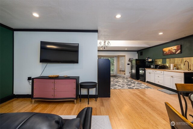 living room with sink, a textured ceiling, light hardwood / wood-style flooring, and a chandelier