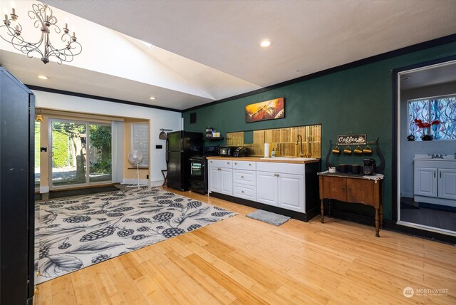 living room with sink, light wood-type flooring, vaulted ceiling, and a notable chandelier