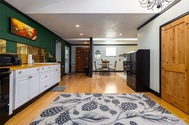 kitchen with sink, light hardwood / wood-style floors, white cabinets, and range