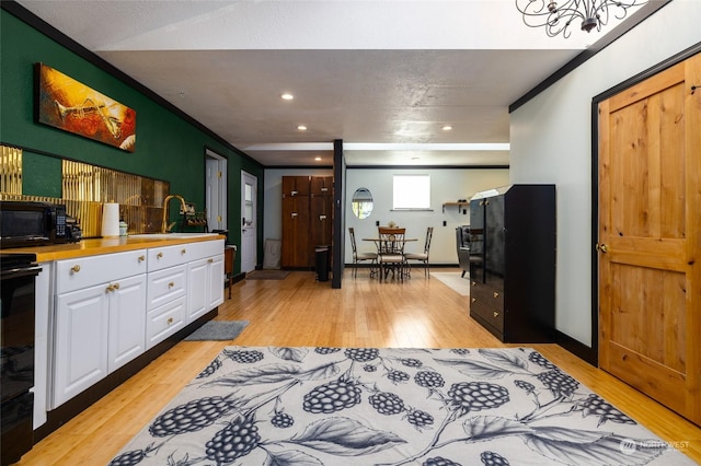 kitchen with recessed lighting, stove, white cabinetry, a sink, and light wood-type flooring