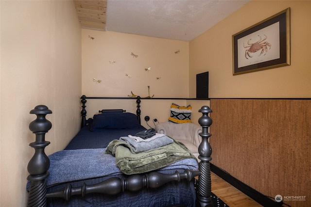 bedroom featuring a wainscoted wall and wood finished floors