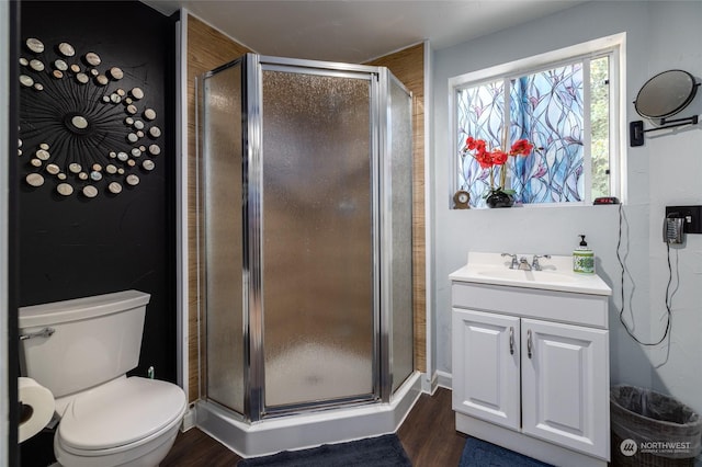 full bath featuring a stall shower, vanity, toilet, and wood finished floors