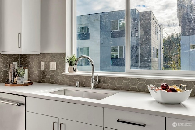 kitchen with backsplash, dishwasher, sink, and white cabinets