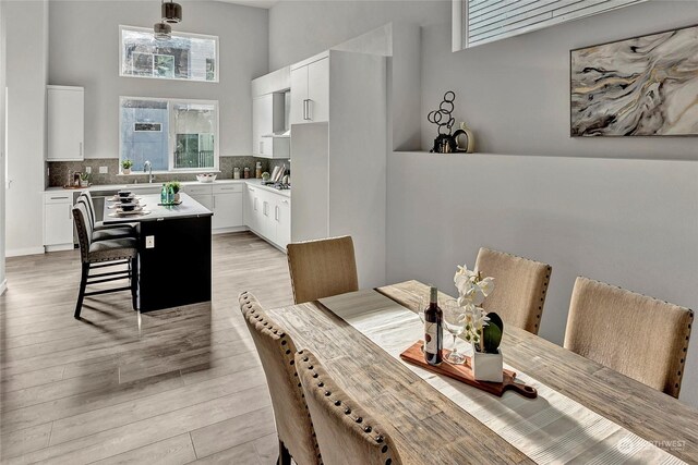 dining space featuring a towering ceiling and light hardwood / wood-style floors