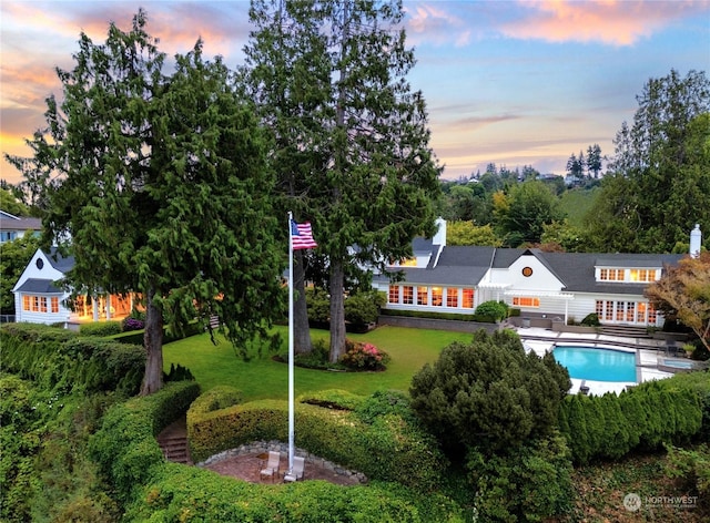 exterior space with a yard, a chimney, and an outdoor pool