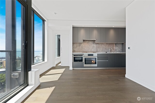 interior space featuring oven, dark hardwood / wood-style flooring, gray cabinetry, and decorative backsplash