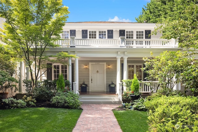 view of front of property with a balcony and a front lawn