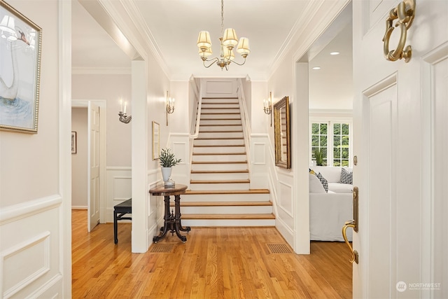 stairs with hardwood / wood-style flooring, crown molding, and an inviting chandelier