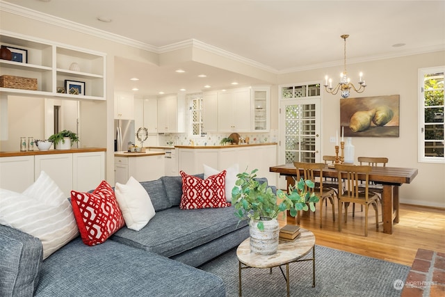 living room with hardwood / wood-style floors, ornamental molding, and a notable chandelier