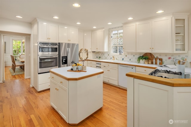 kitchen with a kitchen island, white cabinetry, appliances with stainless steel finishes, and light hardwood / wood-style flooring