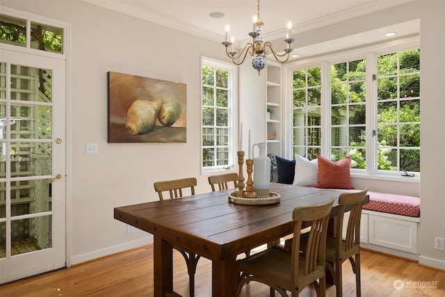 dining space with crown molding, light hardwood / wood-style floors, and an inviting chandelier