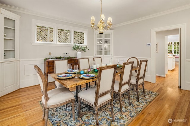 dining room with light wood-type flooring, an inviting chandelier, and crown molding