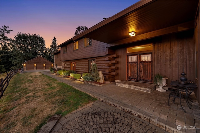 exterior entry at dusk featuring a patio and a yard