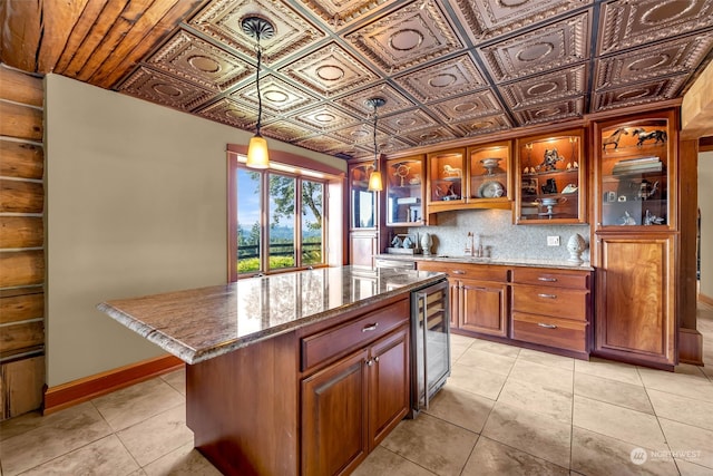 kitchen featuring sink, a center island, decorative light fixtures, beverage cooler, and light stone counters