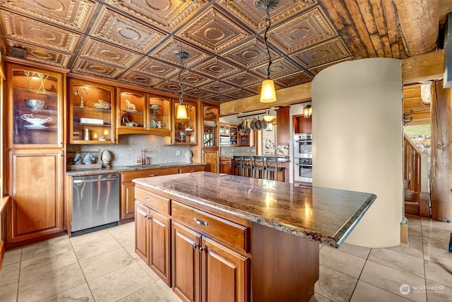 kitchen with stainless steel appliances, dark stone counters, sink, a center island, and pendant lighting