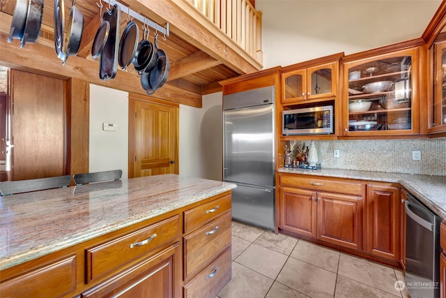 kitchen featuring built in appliances, backsplash, light stone countertops, and light tile patterned floors