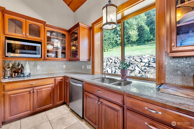 kitchen featuring decorative backsplash, appliances with stainless steel finishes, light stone counters, and vaulted ceiling