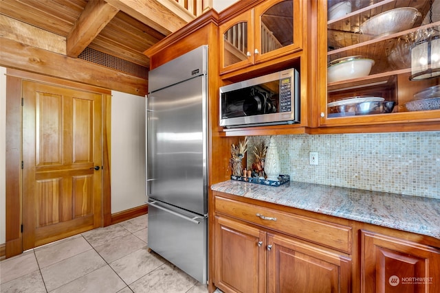 kitchen with wood ceiling, decorative backsplash, light tile patterned floors, built in appliances, and light stone counters