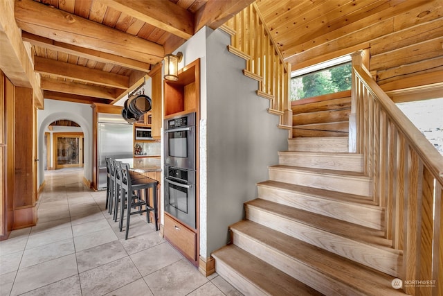 staircase with wood ceiling, beamed ceiling, and tile patterned flooring