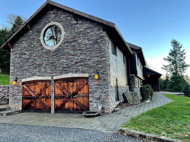 view of side of property featuring a garage and stone siding