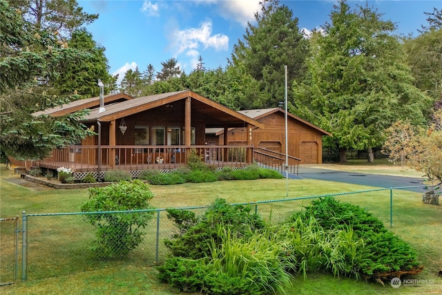 back of property featuring a garage, a wooden deck, and a yard