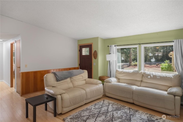 living area featuring wainscoting, wood walls, a textured ceiling, and wood finished floors