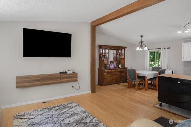 living room featuring lofted ceiling with beams, a textured ceiling, and light wood-type flooring