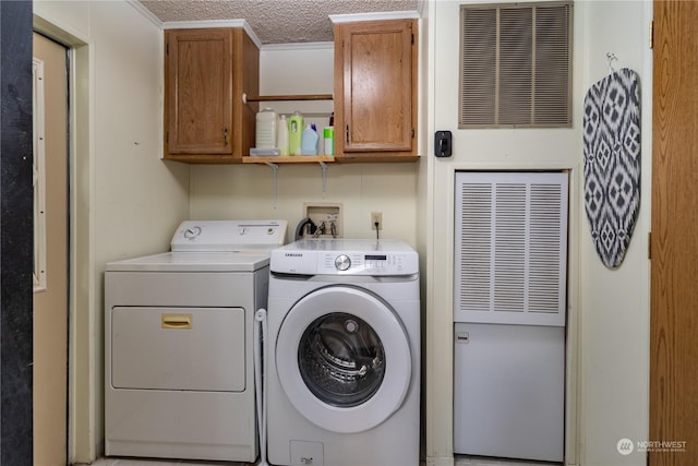 laundry room with cabinet space, washing machine and dryer, visible vents, and a textured ceiling