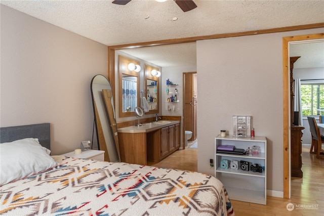 bedroom featuring a textured ceiling, light wood-type flooring, a sink, and ensuite bathroom