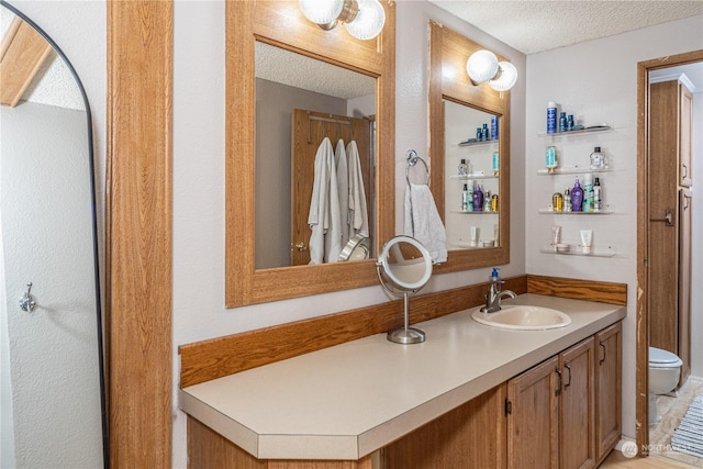 bathroom featuring a textured ceiling, vanity, and toilet