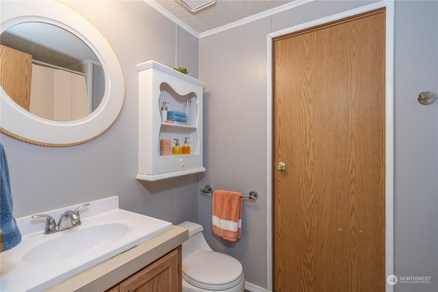 bathroom with crown molding, vanity, toilet, and a textured ceiling