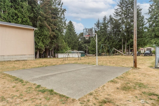 view of sport court featuring a lawn and basketball hoop