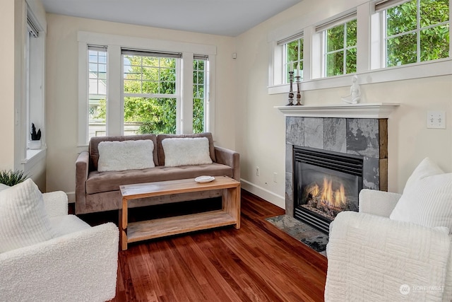 living room featuring dark wood-type flooring, plenty of natural light, and a tile fireplace