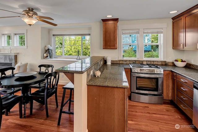 kitchen featuring a breakfast bar area, dark hardwood / wood-style floors, appliances with stainless steel finishes, and ceiling fan