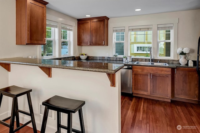 kitchen featuring a kitchen breakfast bar, kitchen peninsula, sink, dark hardwood / wood-style floors, and stainless steel dishwasher