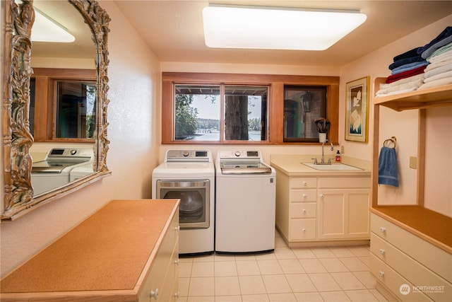 clothes washing area featuring light tile patterned floors, independent washer and dryer, a sink, and cabinet space