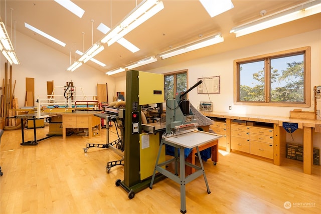 miscellaneous room with a high ceiling, a workshop area, and light wood-style flooring