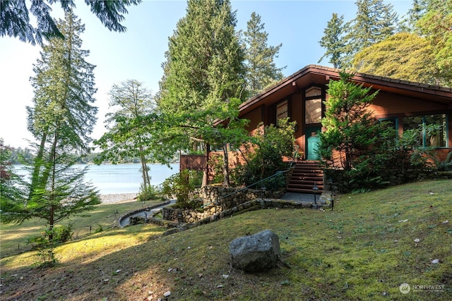 view of front of property with a water view and a front lawn