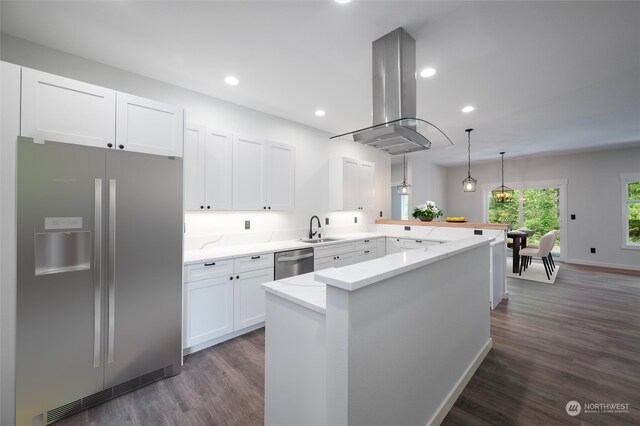 kitchen with dark hardwood / wood-style floors, light stone counters, kitchen peninsula, island range hood, and stainless steel appliances