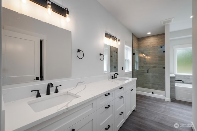 bathroom featuring a wealth of natural light, dual bowl vanity, hardwood / wood-style floors, and separate shower and tub