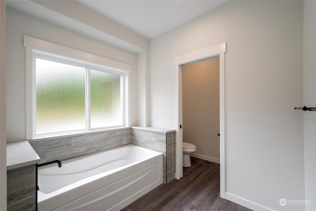 bathroom with a bathtub, toilet, and hardwood / wood-style floors